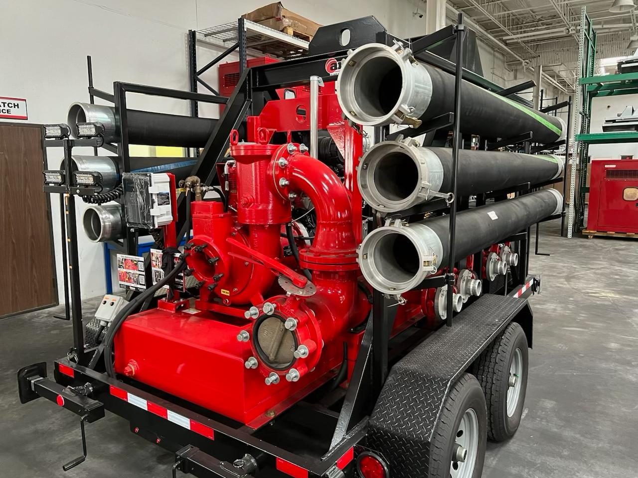 AMCO red trailer-mounted auto-prime dewatering pump with suction hose racks